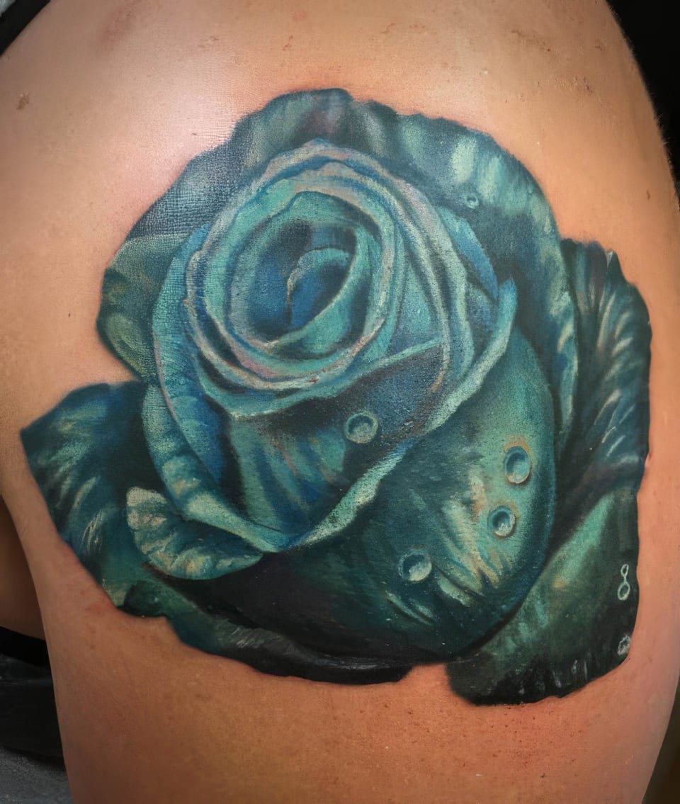 A realistic teal rose with water droplets covers a shoulder.