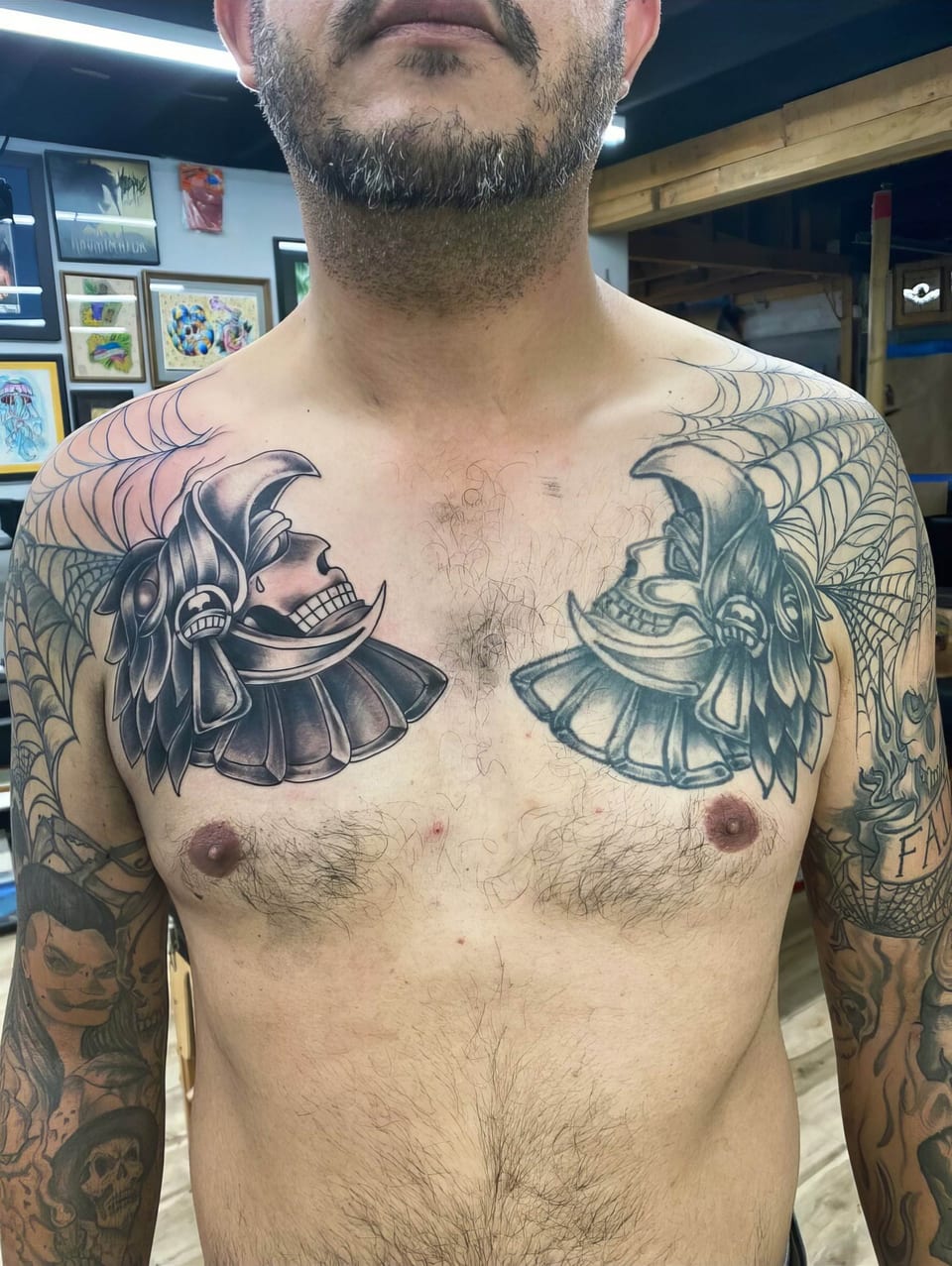 Black and grey Japanese samurai helmets cover a chest beneath shoulder spiderwebs.