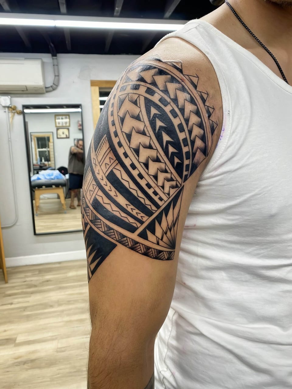 Black Polynesian geometric bands cover a shoulder and upper arm.