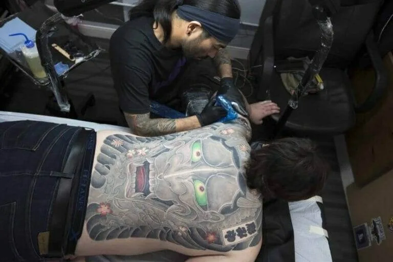 A man is getting a tattoo from Ei Omiya for September's Tattoo Artist Spotlight.