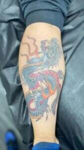 A tattoo of a dragon on a person's forearm.