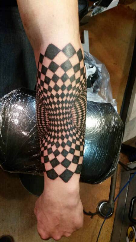 A black and white checkered tattoo on a man's arm.