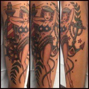 A tattoo of a sailor with a lighthouse and anchor.