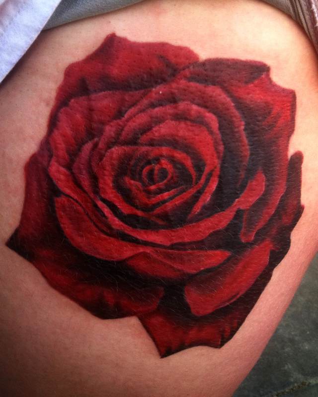 A red rose tattoo on a woman's thigh.