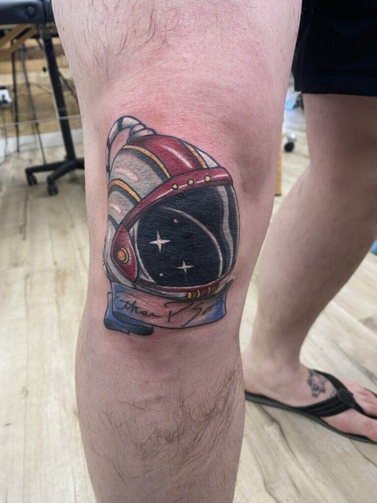 An astronaut helmet tattoo on a man's leg.