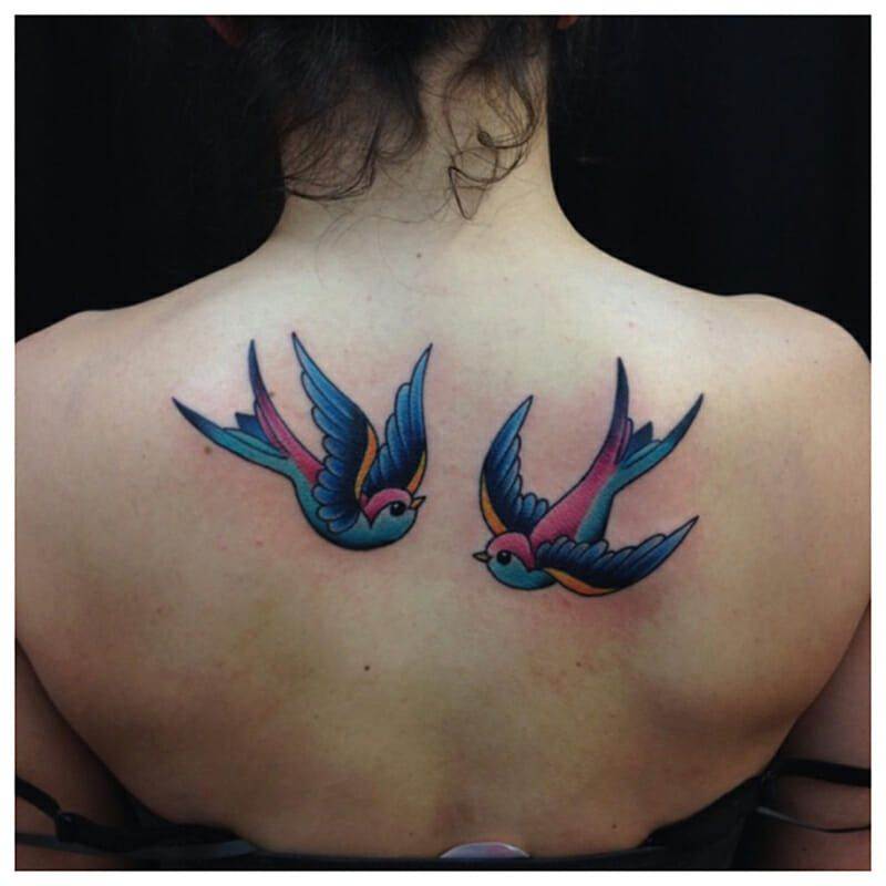 Two swallow tattoos on the back of a woman.