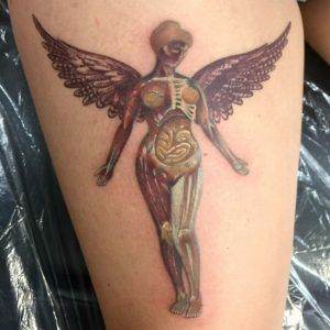 A tattoo of a woman with wings on her thigh.