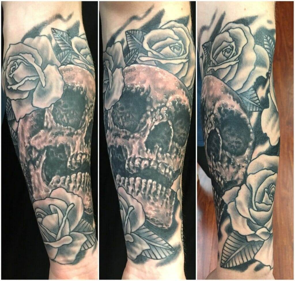 A sleeve tattoo featuring a skull surrounded by roses.