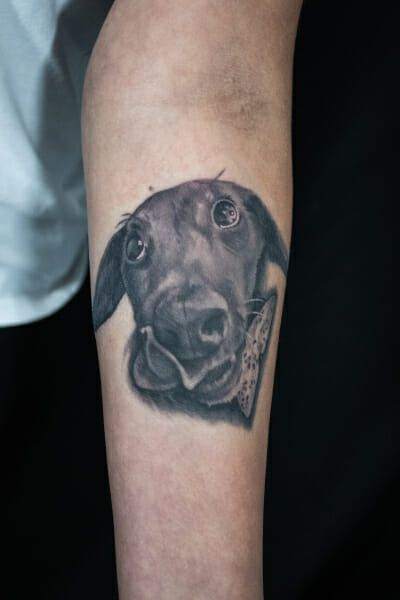 A tattoo of a dog on the forearm.