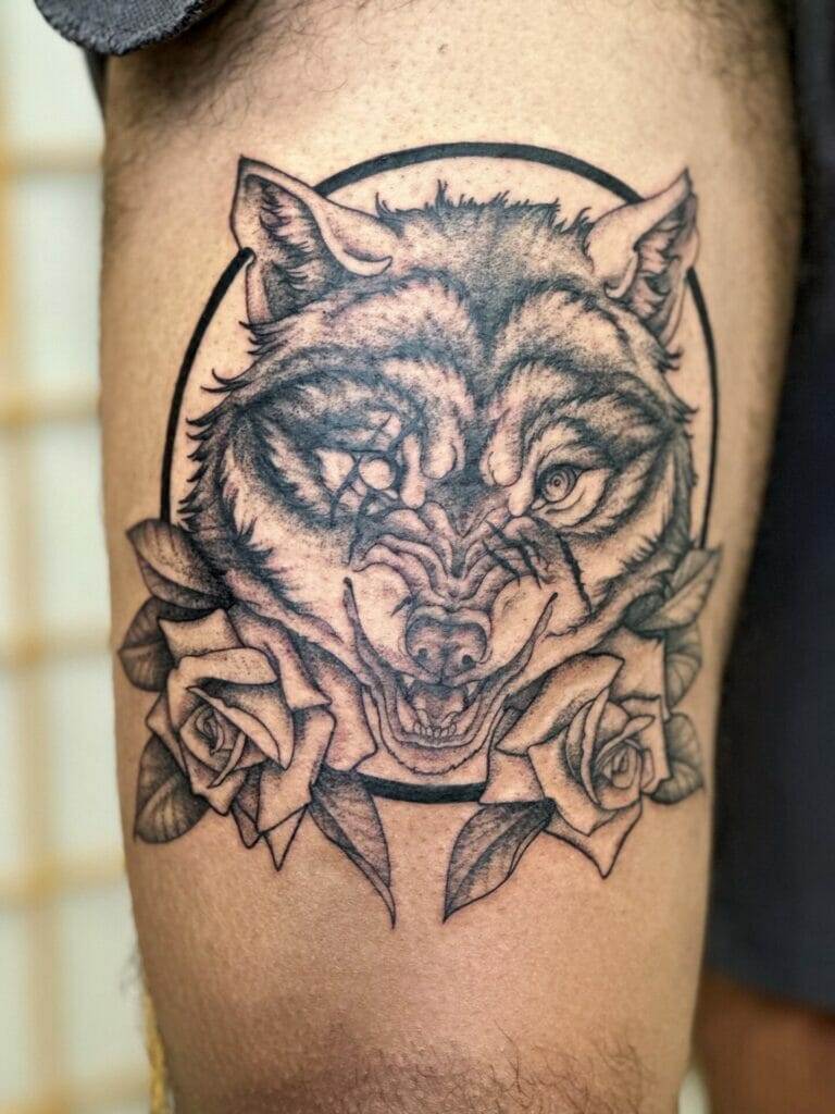 A tattoo of a wolf with roses on his thigh.