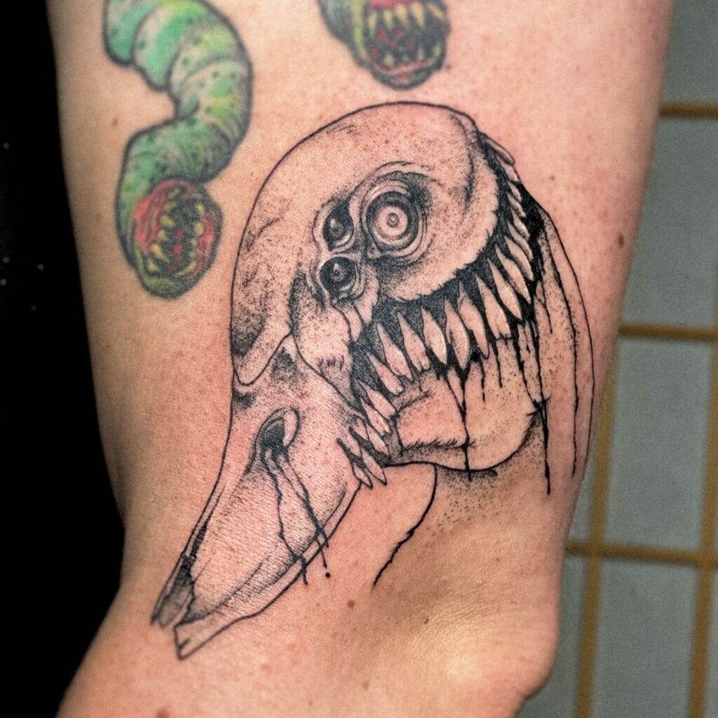 A black and white tattoo of a skull with teeth.