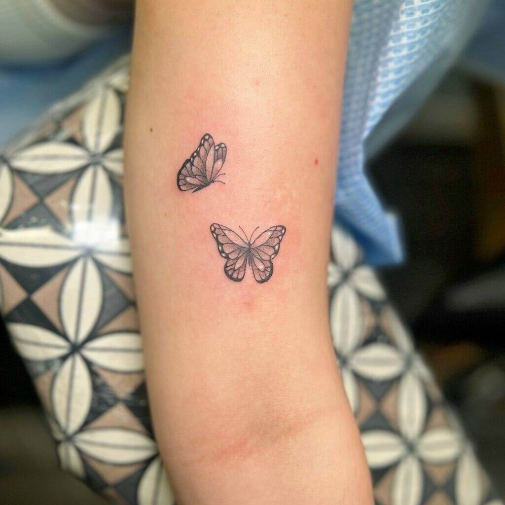 Two small butterfly tattoos on the forearm.