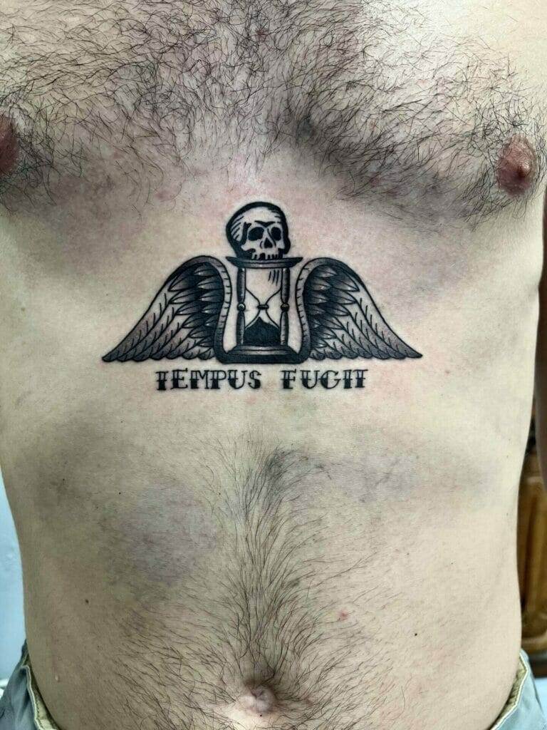 A man with a skull and wings tattoo on his chest.