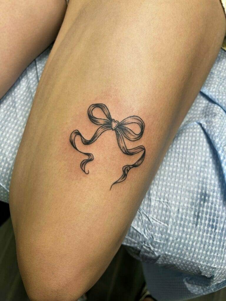 A black and white bow tattoo on a woman's thigh.