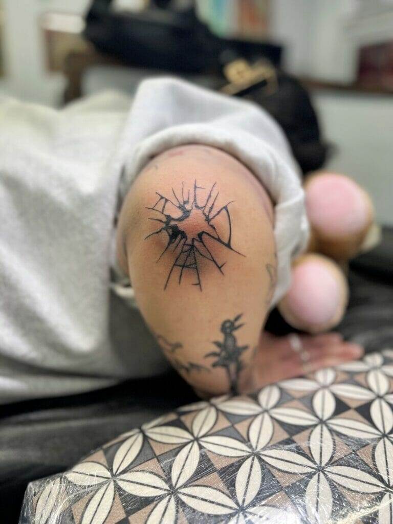 A woman laying on a bed with a tattoo on her arm.