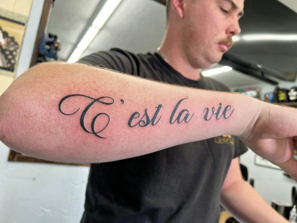 A man with a tattoo that says t est la vie.