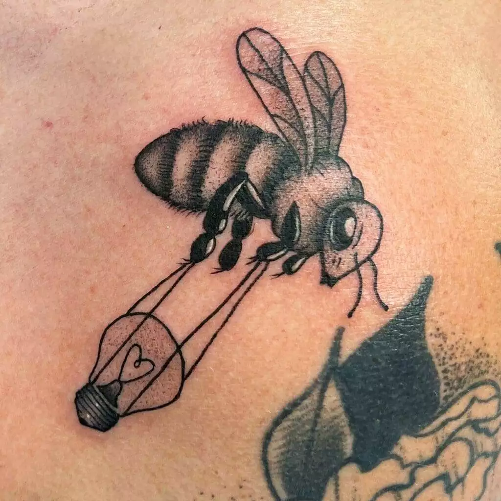 A black and white tattoo of a bee with a lantern.