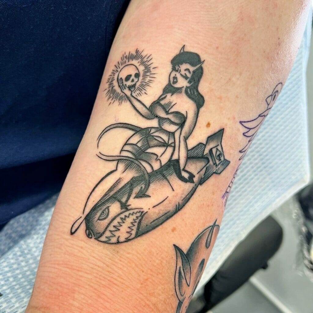 A tattoo of a mermaid riding a boat.