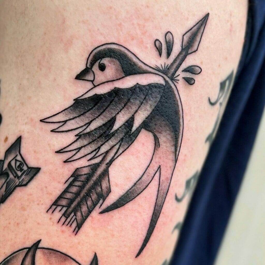 A black and white tattoo of a bird with an arrow.