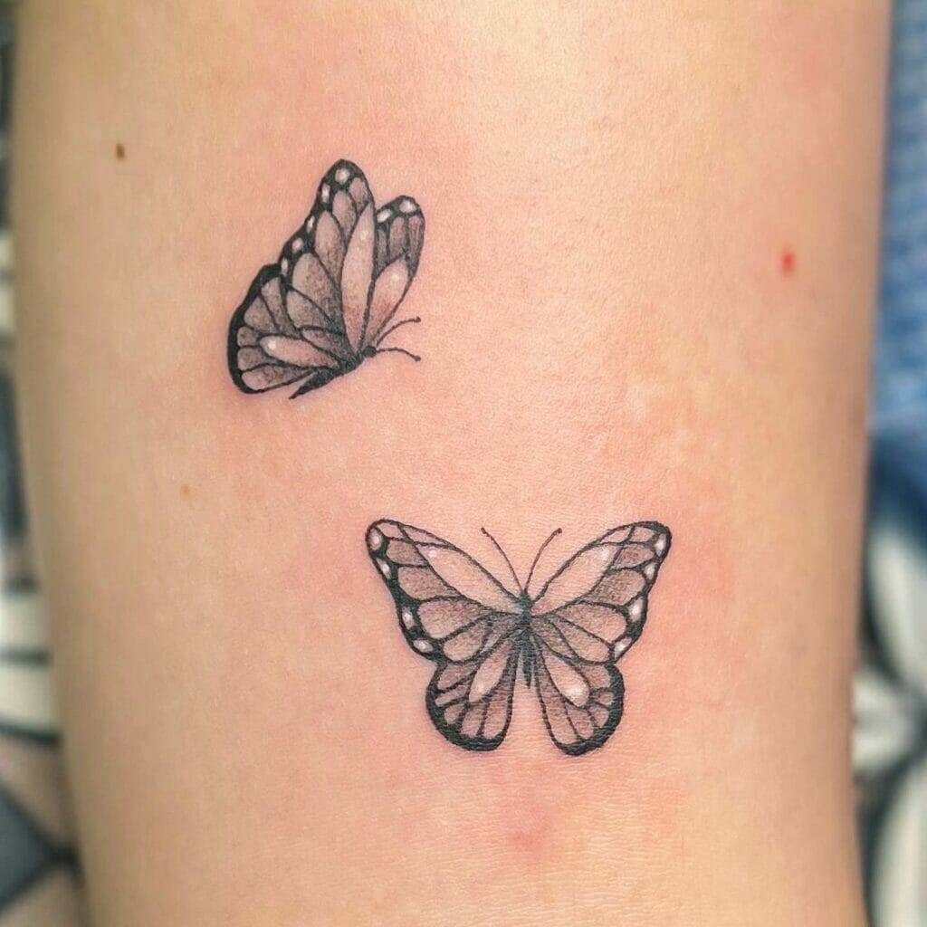 Two small butterfly tattoos on a woman's arm.