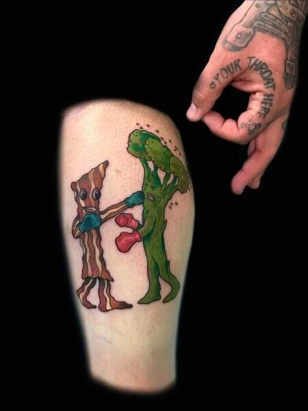 A tattoo of a man with a green alien on his thigh.