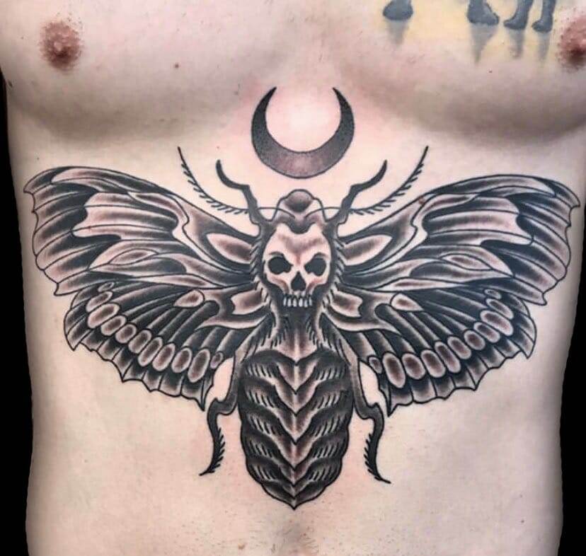 A tattoo of a moth on a man's chest.