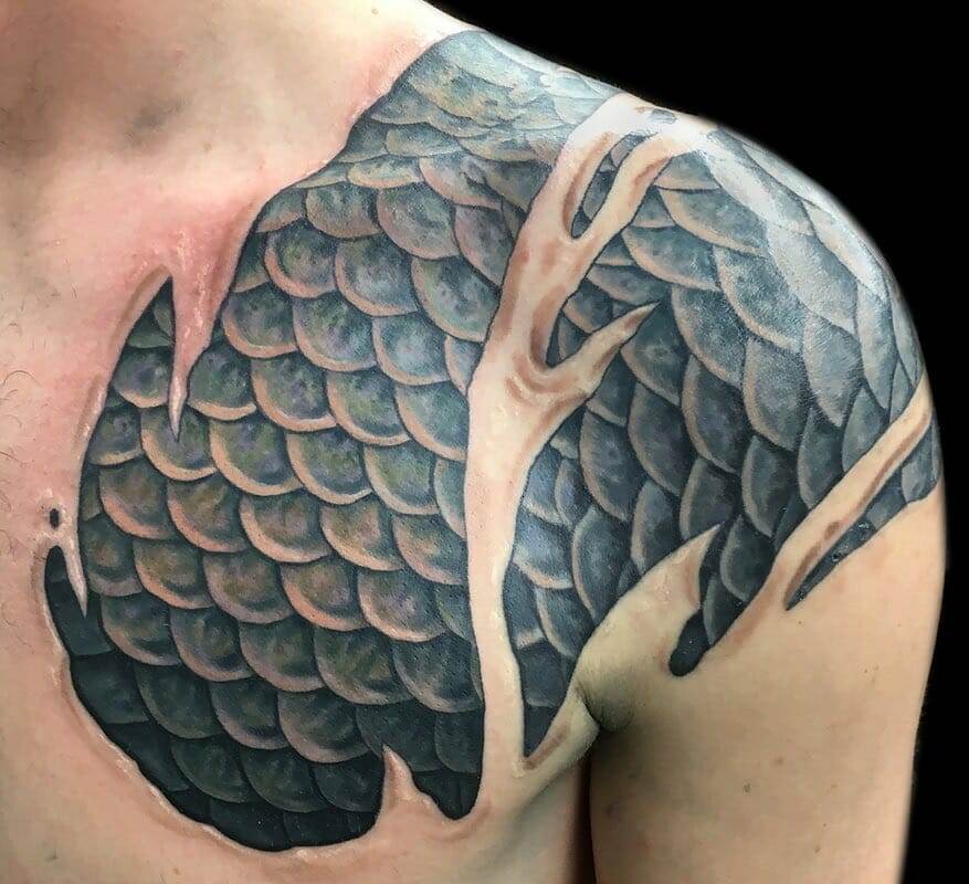 A man with a tattoo of fish scales on his chest.