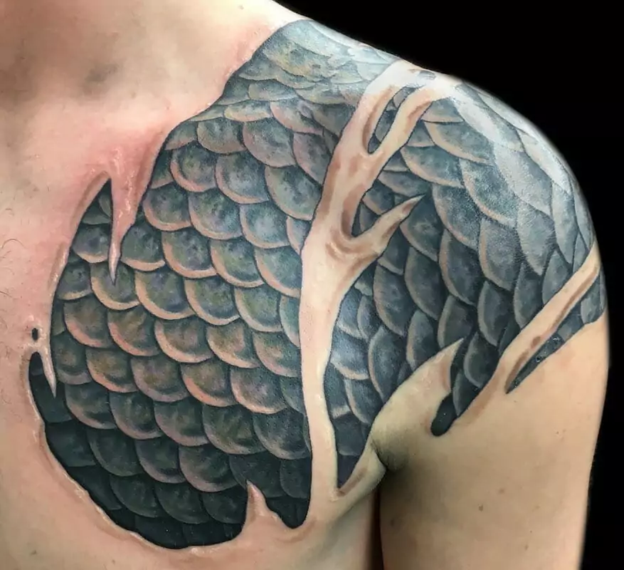 A man with a tattoo of fish scales on his chest.
