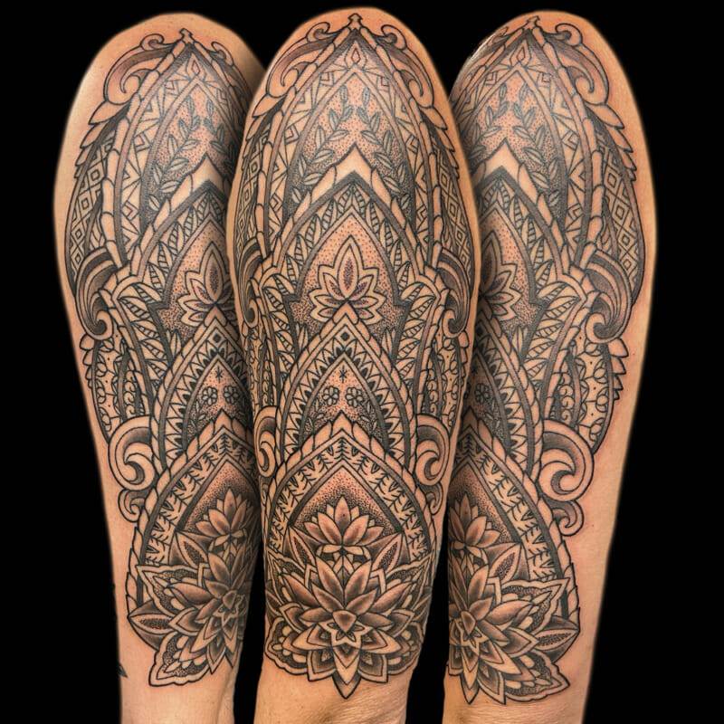 A black and gray tattoo of a mandala on his forearm.