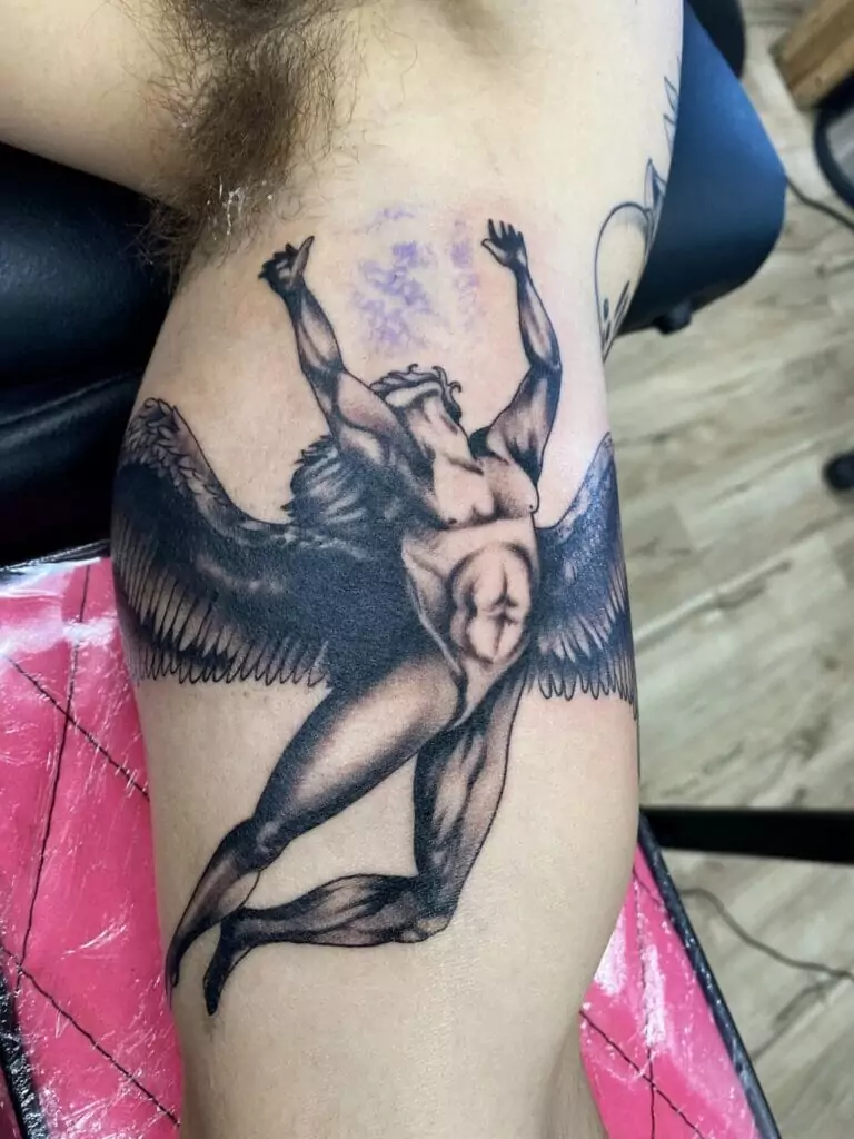 A tattoo of an angel on a man's thigh.