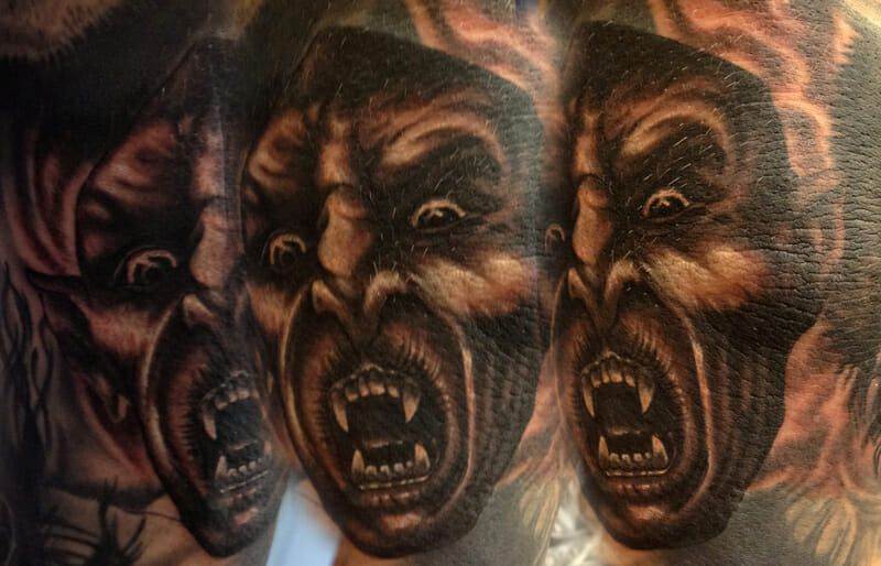 A tattoo of a man with a demon face on his forearm.