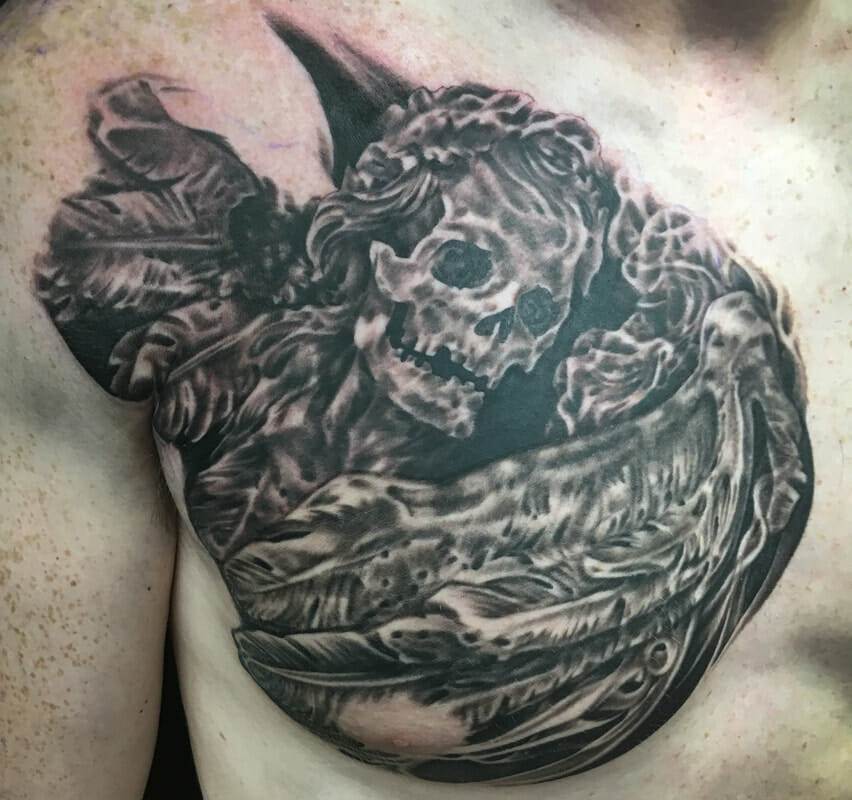 A tattoo of a skeleton with wings on his chest.