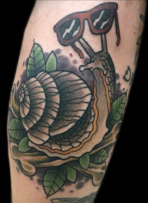 A tattoo of a snail with sunglasses on his leg.