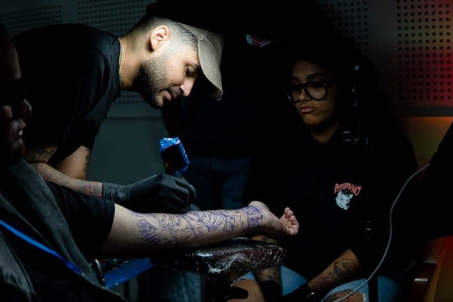 A group of people getting tattoos in a dark room.