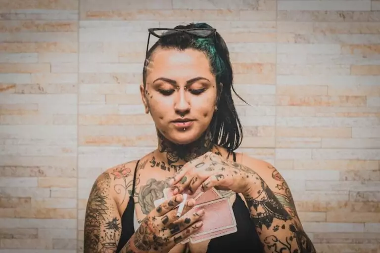A woman with tattoos holding a cigarette.