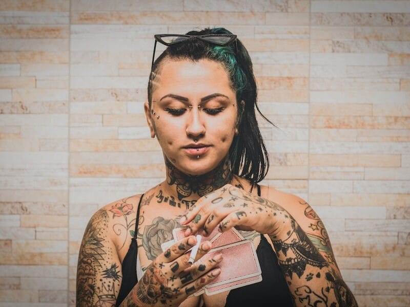 A woman with tattoos holding a cigarette.