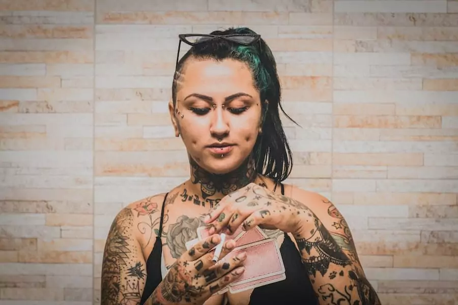A woman with tattoos holding a cigarette.