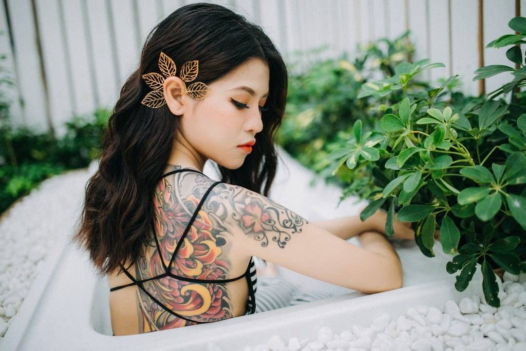 A woman with tattoos sitting in a tub.