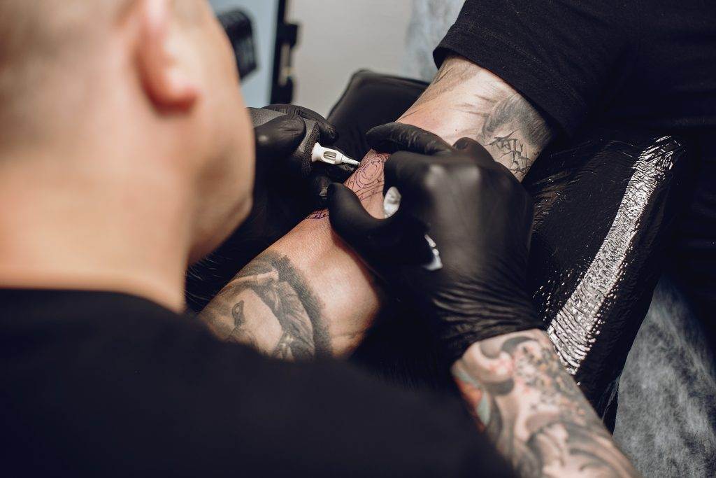 A man receiving a tattoo for a cover-up on his arm showcasing stunning artistry.