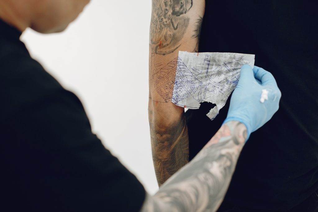 A tattoo artist is creating a stunning work of art on a man's arm, covering unwanted ink with a cover-up tattoo.