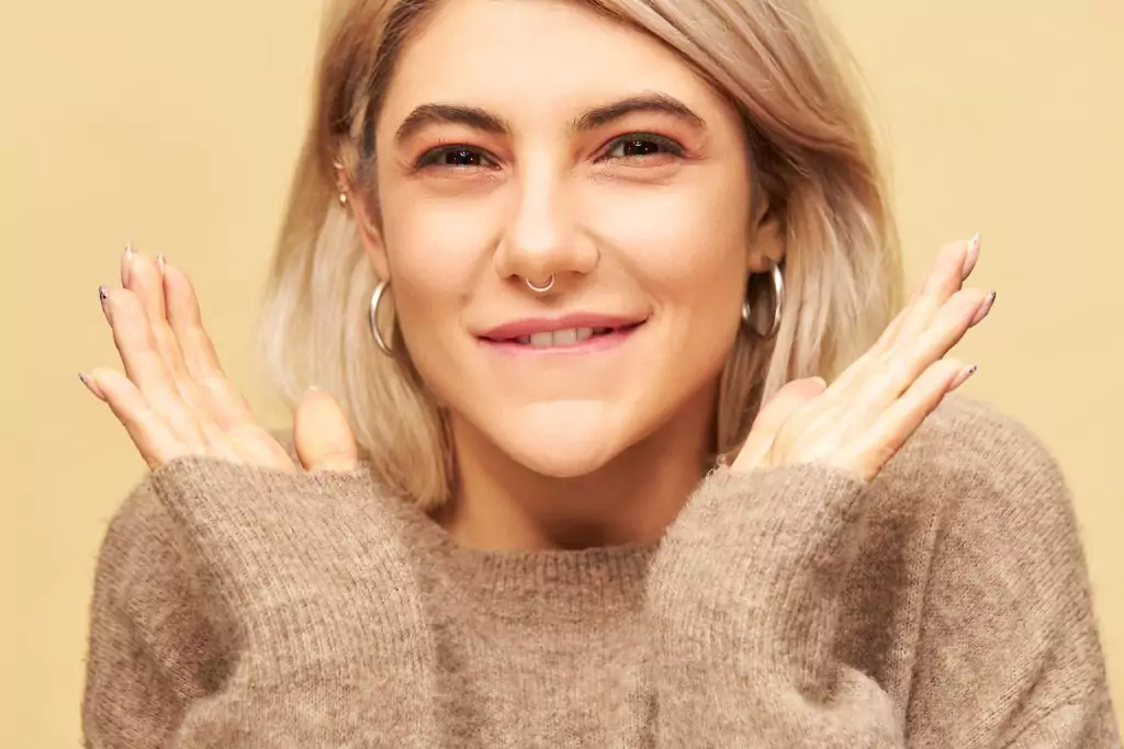 A blonde woman with a smile on her face, receiving a touch-up.