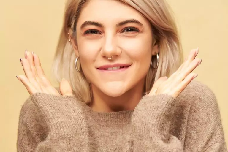 A blonde woman with a smile on her face, receiving a touch-up.