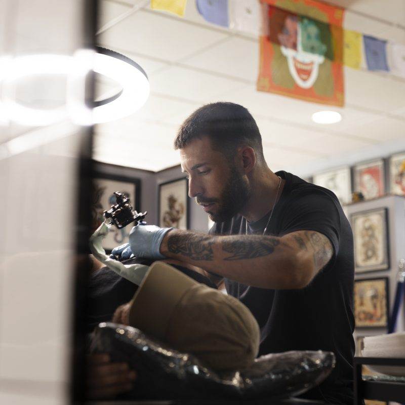 A man receiving a cover-up tattoo, transforming his unwanted ink into a work of art, at a tattoo shop.