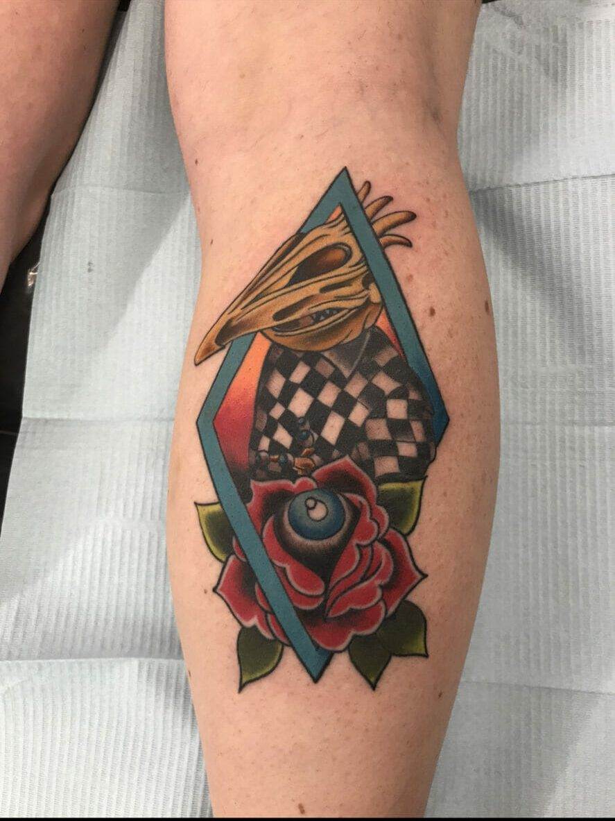 A woman's leg with a tattoo of a rose and a checkerboard.