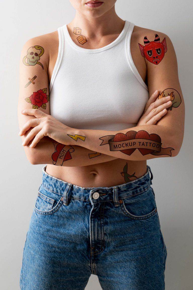Person in a white tank top and jeans with colorful Funhouse Tattoo mockup designs on their arms, including a devil, skull, rose, and lightning bolt, standing with crossed arms in San Diego.