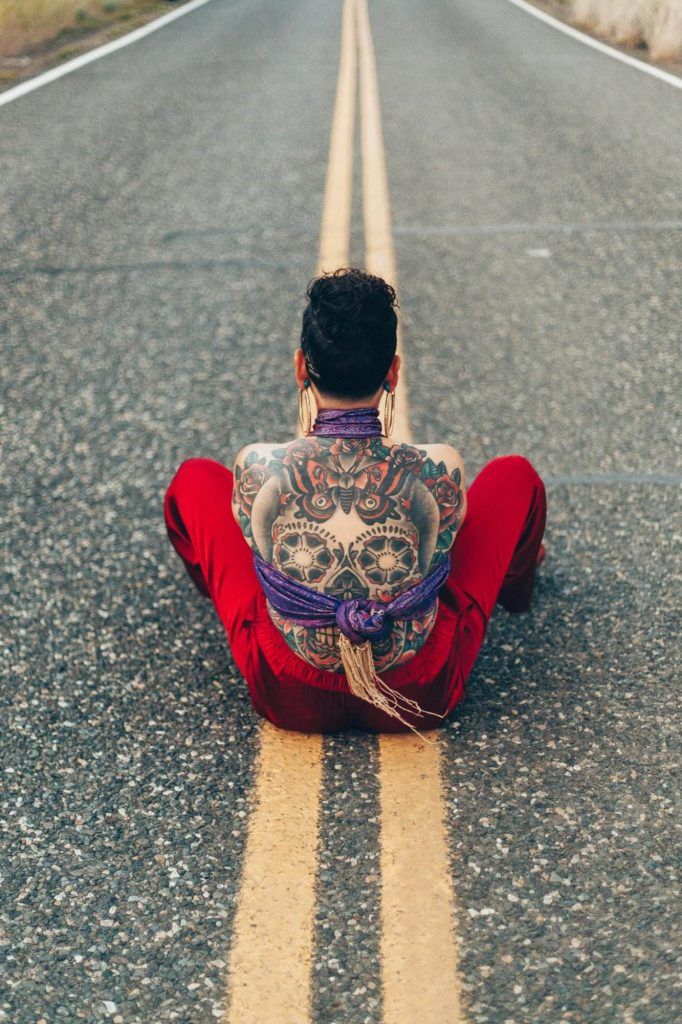 Person With Calavera Tattoo on Back Sitting in Middle of Street