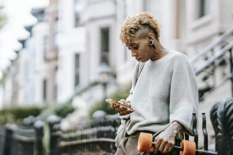 Attentive ethnic woman chatting on smartphone in town