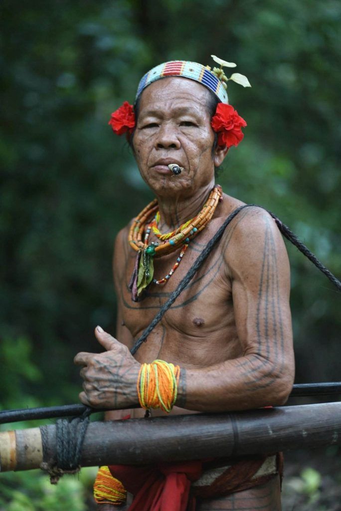 Man Wearing Traditional Tribal Decorations Standing Outside and Smoking