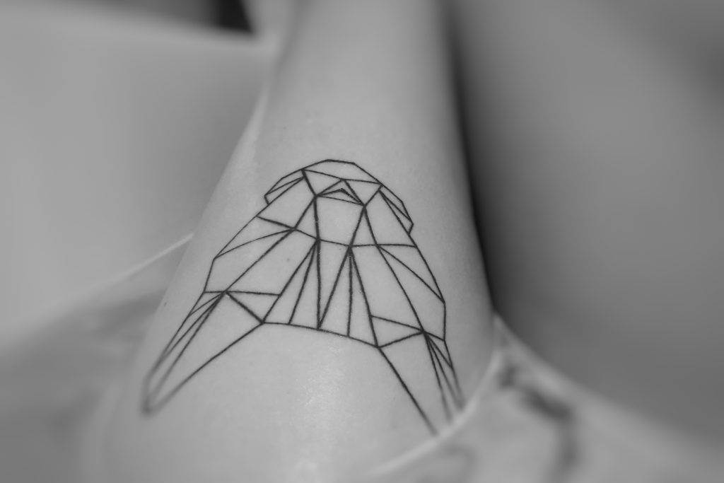 A black line geometric tattoo of an owl on a person's skin, expertly crafted at Funhouse Tattoo in Pacific Beach, showcases the precision of fine line tattoos.