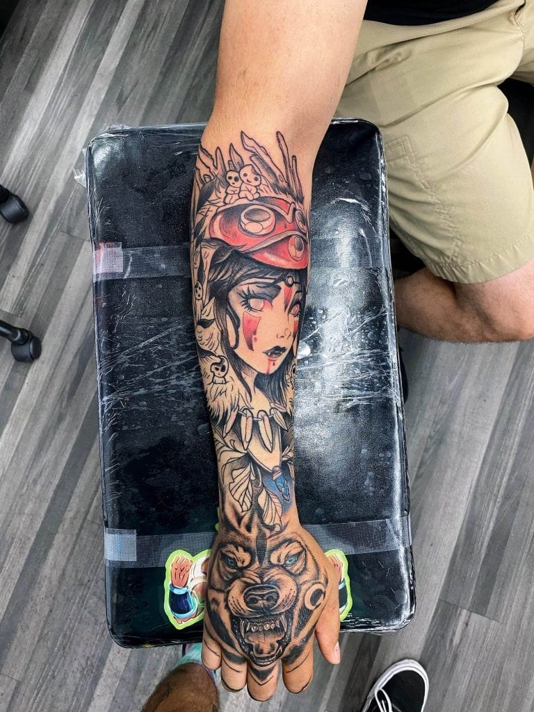 A forearm tattoo features a detailed design with a woman's face and feathered headdress, extending into a wolf's face on the hand.